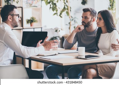 They need an expert advice. Young couple sitting together at the desk and listening to their financial advisor  - Shutterstock ID 431848450