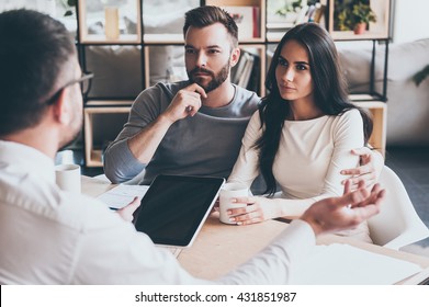 They Need Expert Advice. Young Couple Sitting Together At The Desk And Listening To Their Financial Advisor 