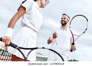 They play like a team. Beautiful young woman and man holding tennis racket and discussing set - Powered by Shutterstock