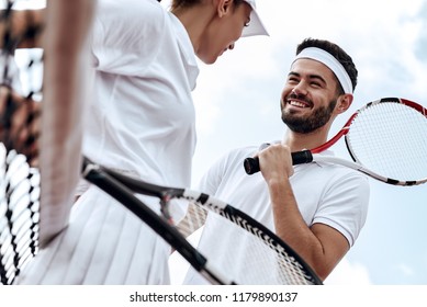 They play like a team. Beautiful young woman and man holding tennis racket and discussing set - Powered by Shutterstock