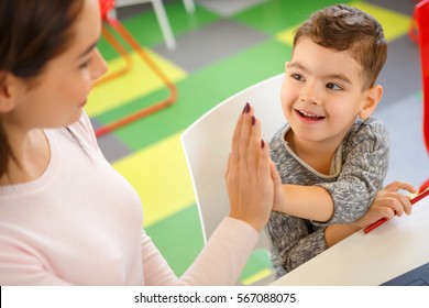 They Are A Team. Top View Shot Of A Cute Little Happy Boy Giving A High Five To His Teacher At Elementary School High Fiving Gesture Team Teamwork Help Education Happiness Friendship Children Concept