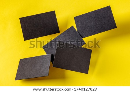 Thick black business cards, flying on a yellow paper background, a mock-up for a creative design presentation