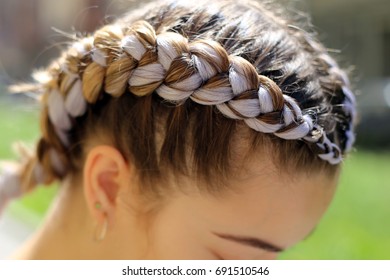 Thick breydy on the head of a girl from a gray kanekalon, artificial hair is woven into a pigtail