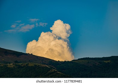 a thick cloud over the mountain on a clear summer day