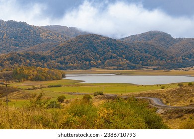 Thick clouds slide down from the mountains and are swirled by the wind. Autumn landscape in the mountains near the lake