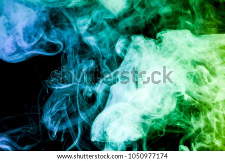 Thick colorful smoke of  blue and  green on a black isolated background. Background from the smoke of vap