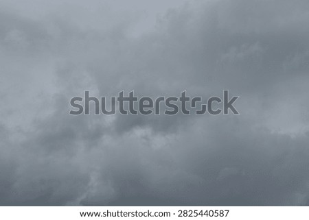 Thick dark gray rain clouds hanging low in the sky before a heavy storm, creating an ominous, frightening and foreboding atmosphere. The dramatic cloudy sky symbolizes danger, bad luck, uncertainty, anxiety, negative emotions, premonition and an approaching threat.