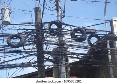 A Thick Jumble Of Electrical Wires Attached To Posts Standing By The Roadside In Dumaguete City, Philippines