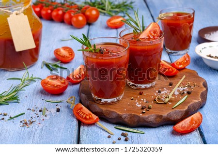 Thick red juice in glass with vegetables and spices on a wooden background. Selective focus.