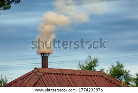 Thick smoke comes out of the chimney into the blue sky