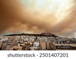 Thick smoke from wildfires in Varvanas and Grammatiko regions engulfs the sky over Athens, Greece, creating a dramatic and ominous scene above the city