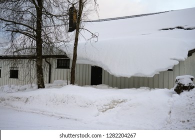 Thick snow hanging on the house roof after winter heavy snowfall.