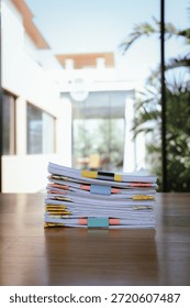 A thick stack of organized documents with colorful paper clips placed on an office desk, representing heavy workload, administration, paperwork, and business documentation.