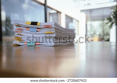 A thick stack of organized documents with colorful paper clips placed on an office desk, representing heavy workload, administration, paperwork, and business documentation.