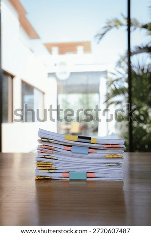 A thick stack of organized documents with colorful paper clips placed on an office desk, representing heavy workload, administration, paperwork, and business documentation.