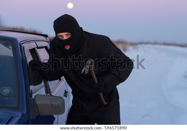 A thief in a black mask, the crowbar broke the\
glass of the machine. theft\
auto