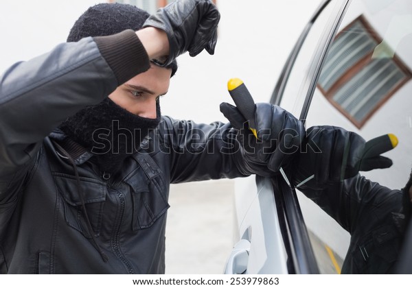 Thief breaking into\
a car in broad daylight