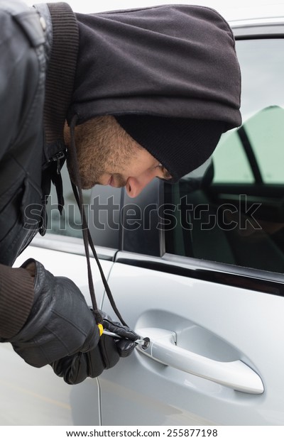 Thief breaking into car with screwdriver in
broad daylight