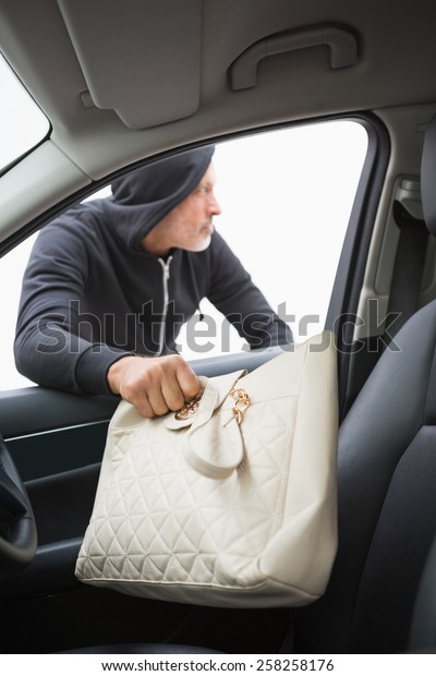 Thief breaking into car and stealing hand bag in
broad daylight