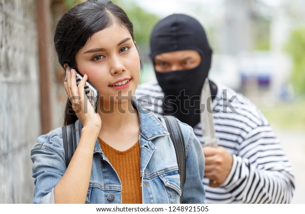 Thief Dangerous man or masked robber with knife\
attacking shoulder bag. Robber or thief holding knife burglarize to\
steal the money wallet in woman\'s bag, while standing near her car\
and don\'t careful