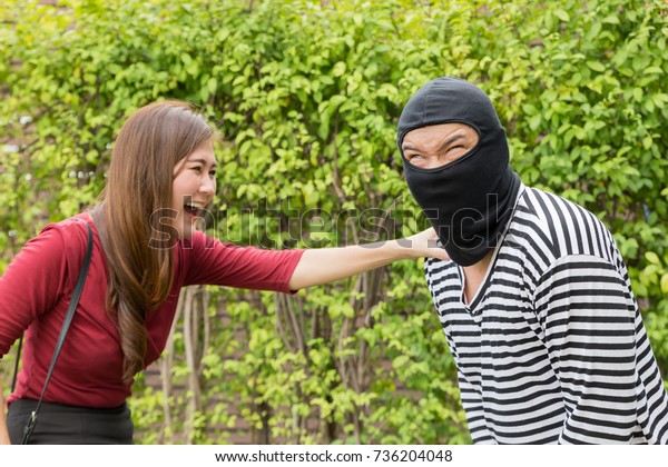 Thief Dangerous man or masked\
robber with a gun attacking shoulder bag. But A beautiful young\
woman fighting to protect themselves. From a robbery that has\
weapons