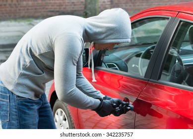 Thief In Hooded Jacket Using Tool And Trying To Steal Car