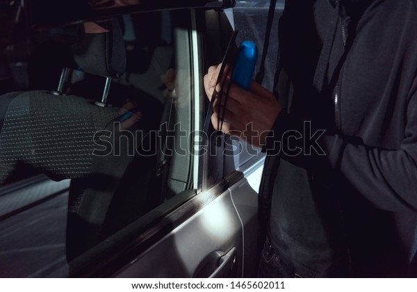 thief intruding\
car with crowbar and\
flashlight