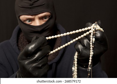 Thief. Man In Black Mask With A Pearl Necklace. Focus On Pearl Necklace