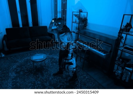 A thief in a mask with a flashlight is captured while rummaging through an apartment at night, depicting a scene of crime and burglary
