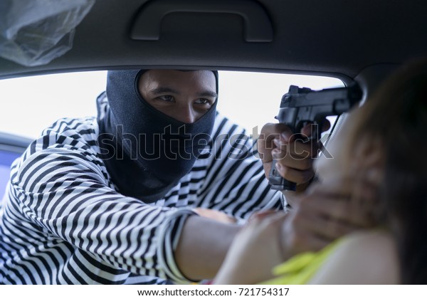 Thief pointing gun to woman\'s head, try to robbery a car\
and ask for property of value such as money,credit card pin code,\
etc. Theft squeezing her neck, she feeling shocked and scared.\
Thief concept 