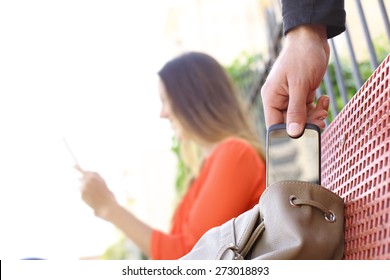 Thief Stealing A Mobile Phone To A Woman Sitting On A Bench In A Park