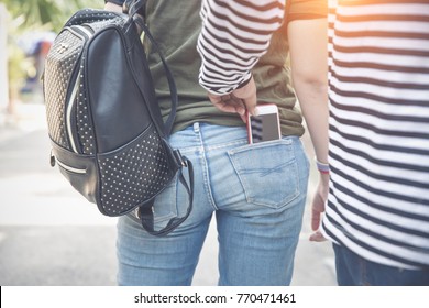 thief stealing smart phone from back pocket jean on street (theft concept)
