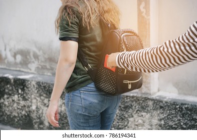 Thief Stealing The Wallet Or Mobile Phone From Behind Young Caucasian Woman Bag On Street, Thief, Crime, Robber And Steal Concept