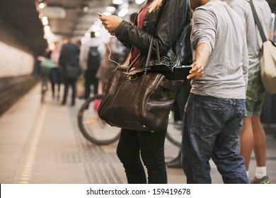 Thief stealing wallet from purse of a woman using mobile phone at the subway station. Pickpocketing at subway station