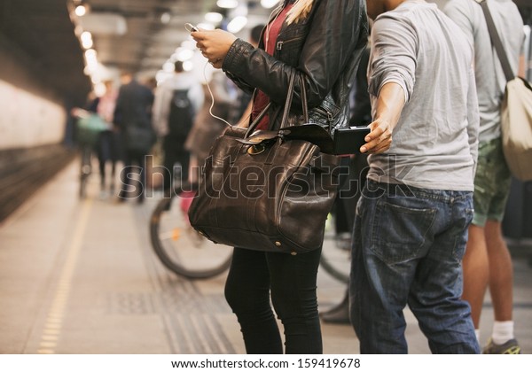 Thief\
stealing wallet from purse of a woman using mobile phone at the\
subway station. Pickpocketing at subway\
station