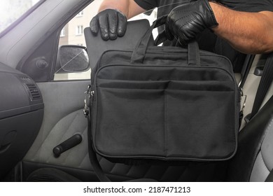 Thief Steals A Laptop Bag From The Passenger Seat From An Open Car Window. View From Inside The Automobile Interior. Concept Of Robbery.