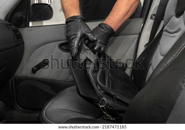Thief steals a laptop bag from the passenger\
seat from an open car window. View from inside the automobile\
interior. Concept of\
robbery.