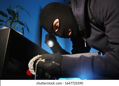 Thief Taking Jewelry Out Of Steel Safe Indoors At Night