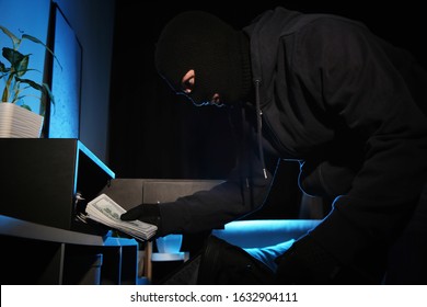 Thief taking money out of steel safe indoors at night - Shutterstock ID 1632904111
