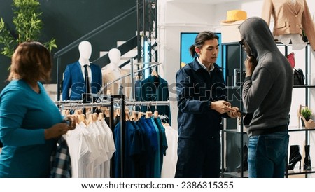 Thief trying to stole trendy clothes from modern boutique, being caught by asian bodyguard. African american couple arguing with store worker and security guard, trying to escape crime accusation