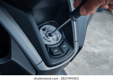 thief using a screwdriver tool to break into a motorcycle ignition lock, representing vehicle theft and security vulnerabilities. Ideal for news crime prevention campaigns, insurance agency websites