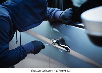 Thief Using A Tool To Break Into A Car.