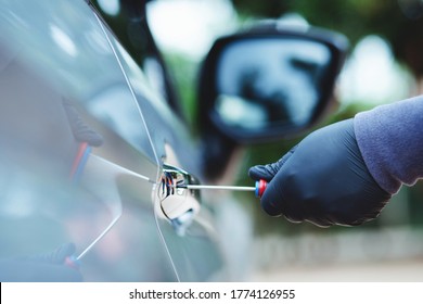 Thief Using A Tool To Break Into A Car.