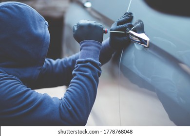 Thief Using A Tool To Break Into A Car.