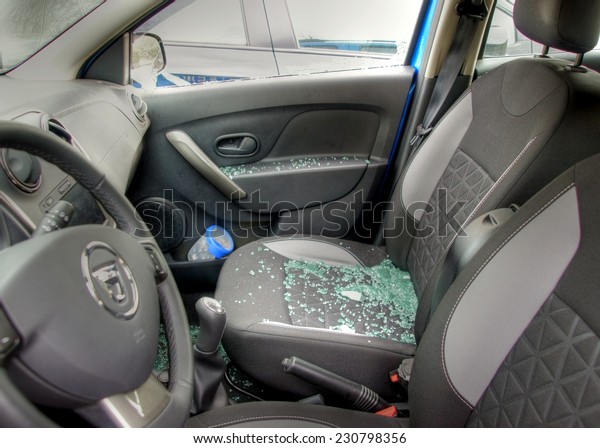 Thiefs have broken a car\
window to steel items inside  and the glass is spread all over the\
car seats 