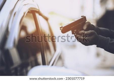 Thieves are using guns to rob a car, threatening a woman with car keys.