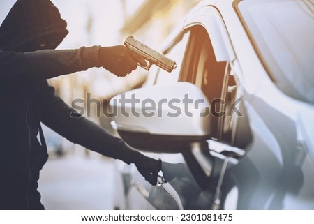 Thieves are using guns to rob a car, threatening a woman with car keys.
