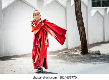 Thiksay Monastery in Thiksey village, India – August 20, 2016: Young monk boy goes by the monastery weared in traditional red kasaya  in Thiksey village, India