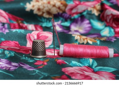 Thimble With Needle and Pink Thread on Vintage Floral Satin Fabric