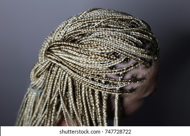 a lot of thin African plaits with artificial material, blond close-up on a light background, beauty studio 